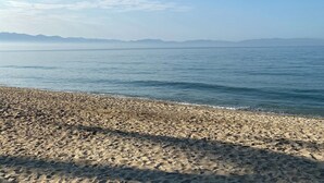 En strand med en stenig kust och stilla vatten.