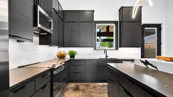 Una cocina moderna con muebles oscuros, una isla central y un ventanal con vistas.