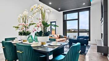 Un comedor moderno con una mesa dispuesta para cuatro personas, sillas color turquesa y un amplio ventanal con vistas al exterior.