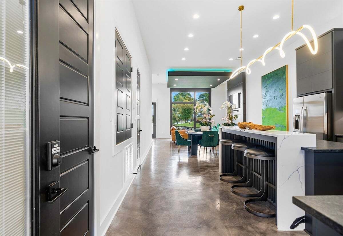 Una cocina moderna con barra, una mesa de comedor y sillas, y vistas al exterior.