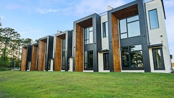 Un edificio moderno de varios pisos con techo plano, ventanas amplias y un césped.