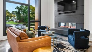 A modern living room with a large window, a fireplace, and a flat-screen TV mounted on the wall. - Modern Retreat with Rooftop and Lake Access (Hot Springs)