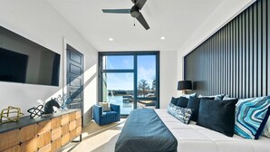 A modern bedroom with a bed, a desk, a chair, and a view of the outdoors.