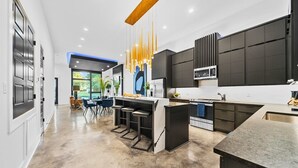 A modern kitchen with a central island, bar stools, and pendant lighting.