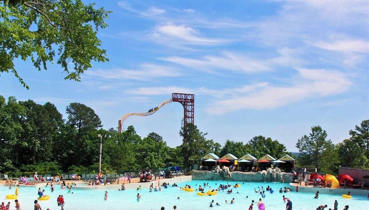 Een waterpark met een hoge glijbaan, diverse zwembaden en schaduwrijke plekken.