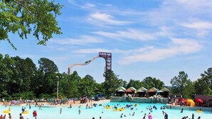 A water park with a tall water slide, multiple pools, and shaded areas.