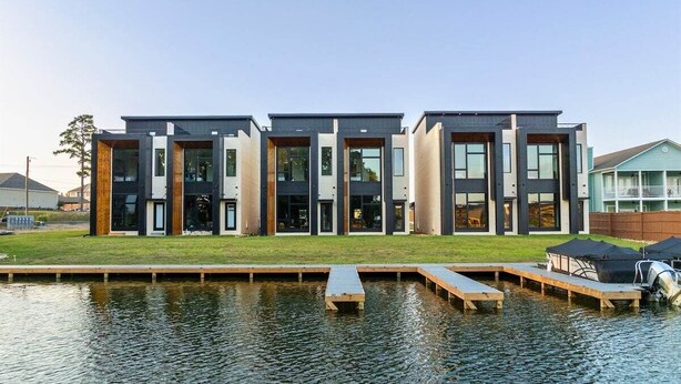 A modern building with a flat roof, large windows, and a dock extending into a body of water.