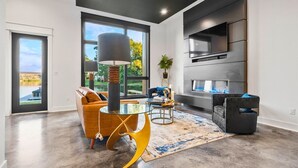 A modern living room with a sofa, a coffee table, a lamp, and a TV mounted on the wall.