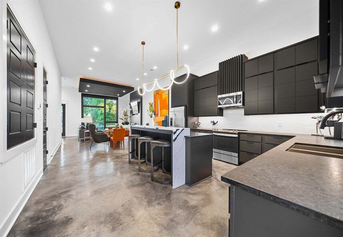 Una cocina moderna con una isla central, taburetes de bar e iluminación colgante.