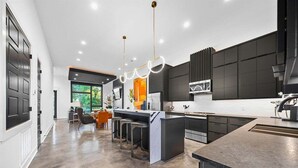Een moderne keuken met een centraal eiland, barstoelen en hanglampen.