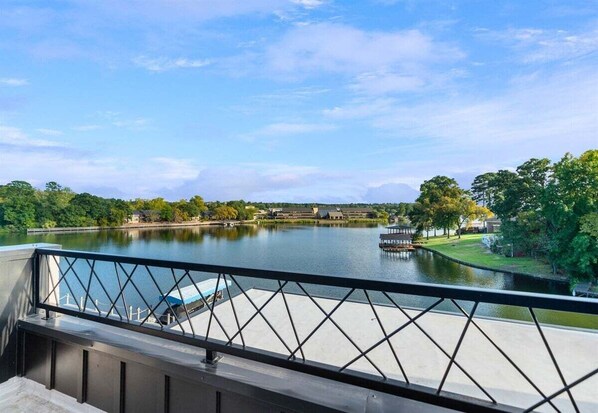 A river view from a balcony with a railing, a dock, and buildings in the background. - Modern Retreat with Rooftop and Lake Access (Hot Springs)
