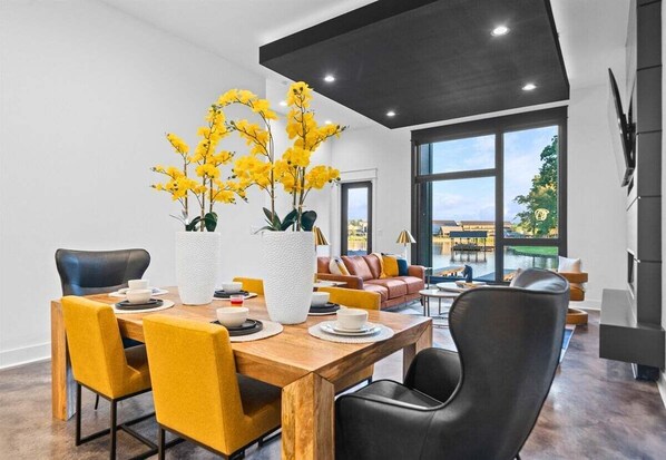 Un espace repas moderne avec une table en bois, des chaises jaunes et un vase rempli de fleurs jaunes.