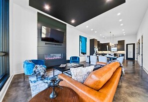 A modern living room with a fireplace, leather sofa, and a flat-screen TV.