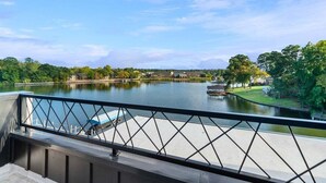 A river view from a balcony with a railing, a dock, and buildings in the background. - Modern Retreat with Rooftop and Lake Access (Hot Springs)