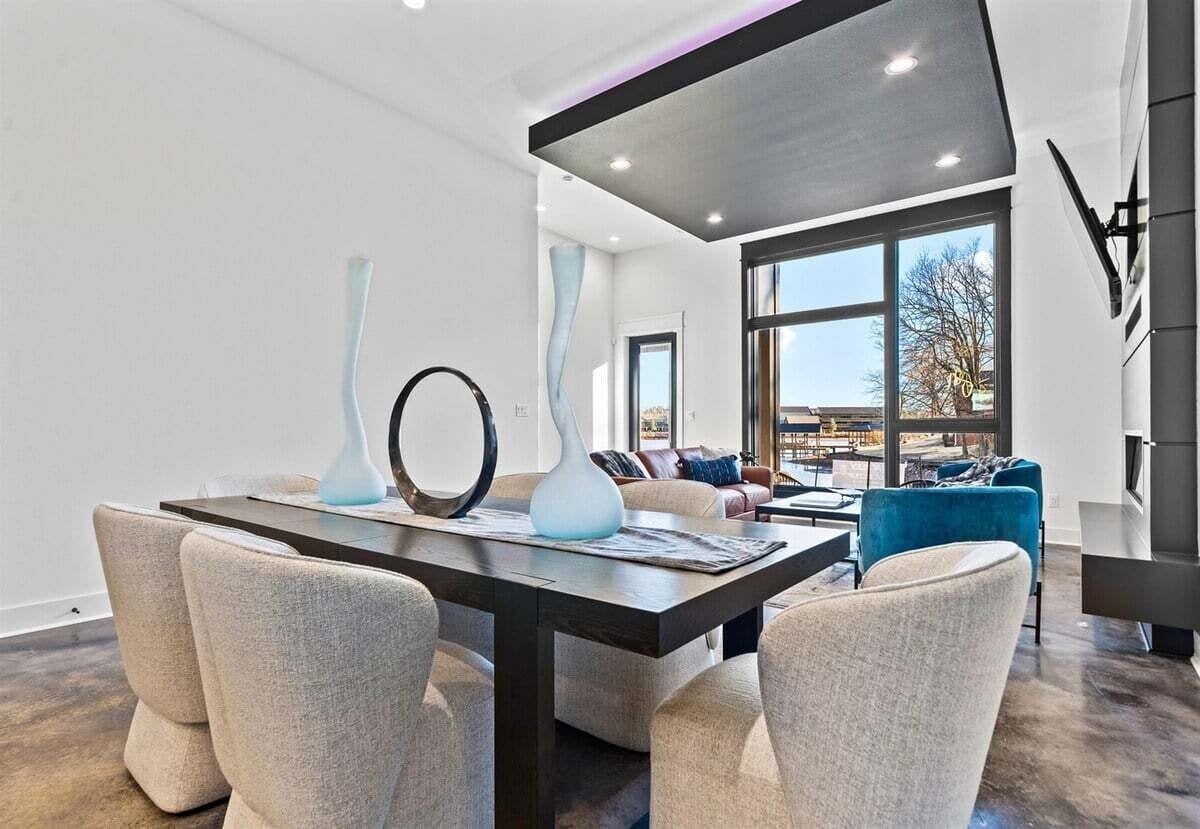 Una sala de estar moderna con comedor, ventanas amplias y muebles contemporáneos.