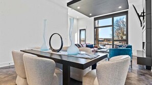 A modern living room with a dining area, large windows, and contemporary furniture. - Modern Retreat with Rooftop and Lake Access (Hot Springs)