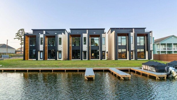 A modern building with a flat roof, large windows, and a dock extending into a body of water. - Modern Retreat with Rooftop and Lake Access (Hot Springs)
