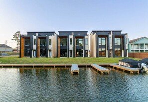 A modern building with a flat roof, large windows, and a dock extending into a body of water.