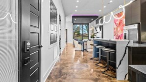 A modern kitchen with a marble countertop, a built-in oven, and a dining area with a table and chairs.