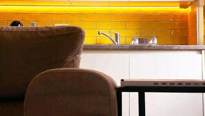 Una cocina con armarios blancos, salpicadero amarillo y un lavabo.
