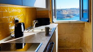 Una cocina con un ventanal grande, azulejos amarillos y vistas a un pueblo costero.