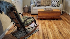 A cozy living room with a rocking chair, a sofa, and a coffee table.