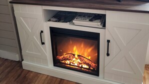 A fireplace with a TV above it, a thermostat above the TV, and a framed picture to the right.
