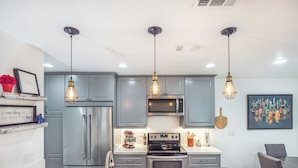Una cocina moderna con gabinetes grises, electrodomésticos de acero inoxidable e iluminación colgante.
