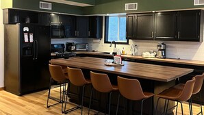 A modern kitchen with a central island, black cabinets, and a wooden dining table with four chairs.