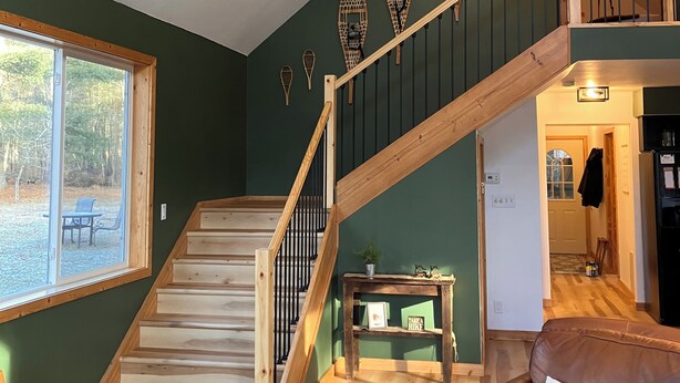 A spacious living area with a wooden staircase, a large window, and a view of the outdoors.