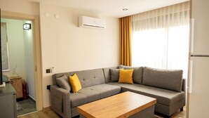 Una sala de estar moderna con un sofá seccional gris, una mesa de centro de madera y un ventanal con cortinas amarillas.