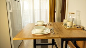 Una mesa de comedor dispuesta con fuentes y platos blancos, cubiertos y una bandeja con dos tazas y un vaso.