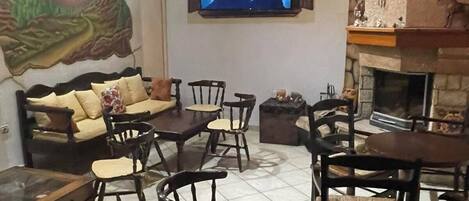 A cozy living room with a stone fireplace, wooden furniture, a mounted TV, and a mural on the wall.