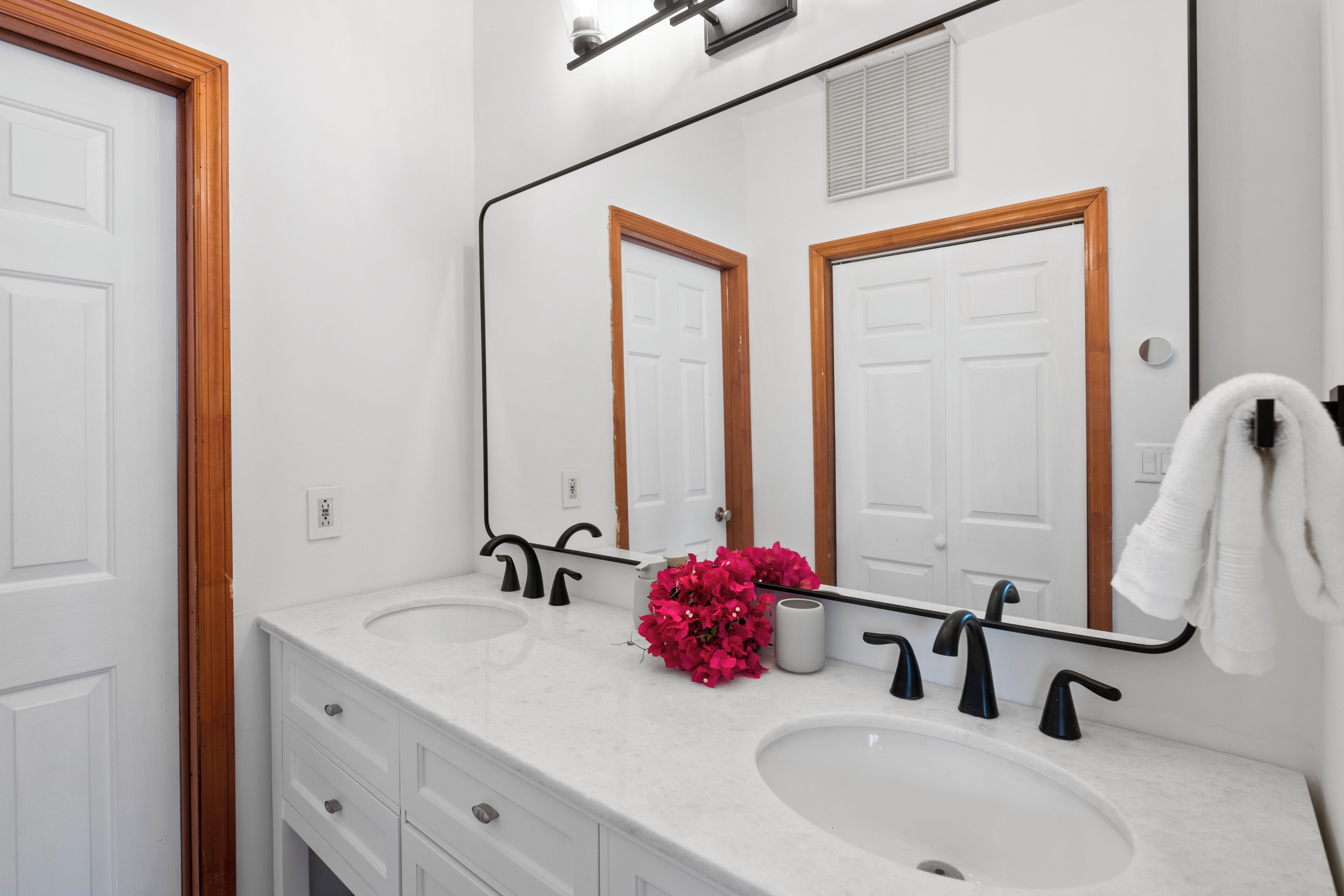 A bathroom with two sinks, a mirror, and a towel rack.