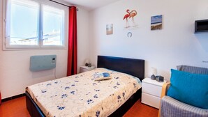 Una habitación de hotel con cama, mesita de noche, una silla, ventana con cortinas y decoración en la pared.