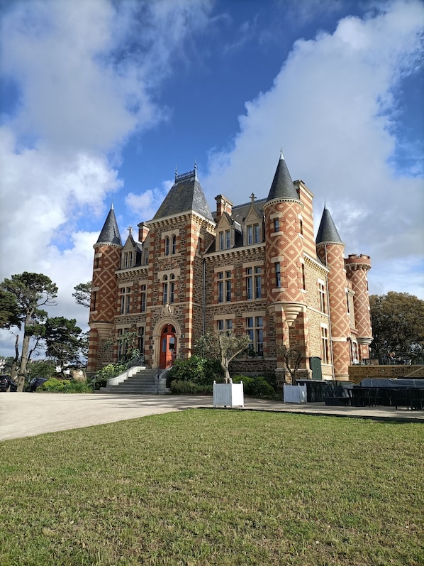 A large, historic building with multiple towers and a central entrance.