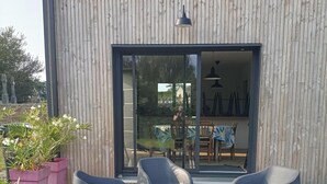 A modern outdoor seating area with plastic chairs and a table, surrounded by potted plants. - Village house 5 mn walk from shops and 10 mn from beaches.  (Saint-Briac-sur-Mer)