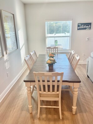 Comedor con una mesa larga, seis sillas y un centro de mesa floral.
