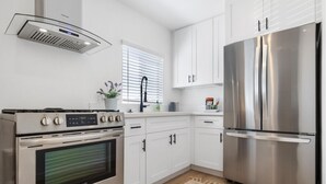 Une cuisine moderne dotée d’appareils électroménagers en acier inoxydable, de meubles blancs et d’un four encastré.