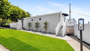 Une maison mobile de plain-pied, avec une façade blanche, un porche à l’avant et un petit escalier menant à l’entrée.