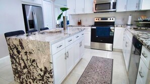 Una cocina moderna con armarios blancos, electrodomésticos de acero inoxidable y encimera de granito.