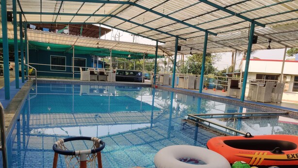A swimming pool with a covered area, lounge chairs, and inflatable toys. - Supriti's Farmington Splash Resort (Karjat)