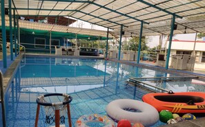 Una piscina con zona cubierta, sillas de descanso y juguetes inflables.