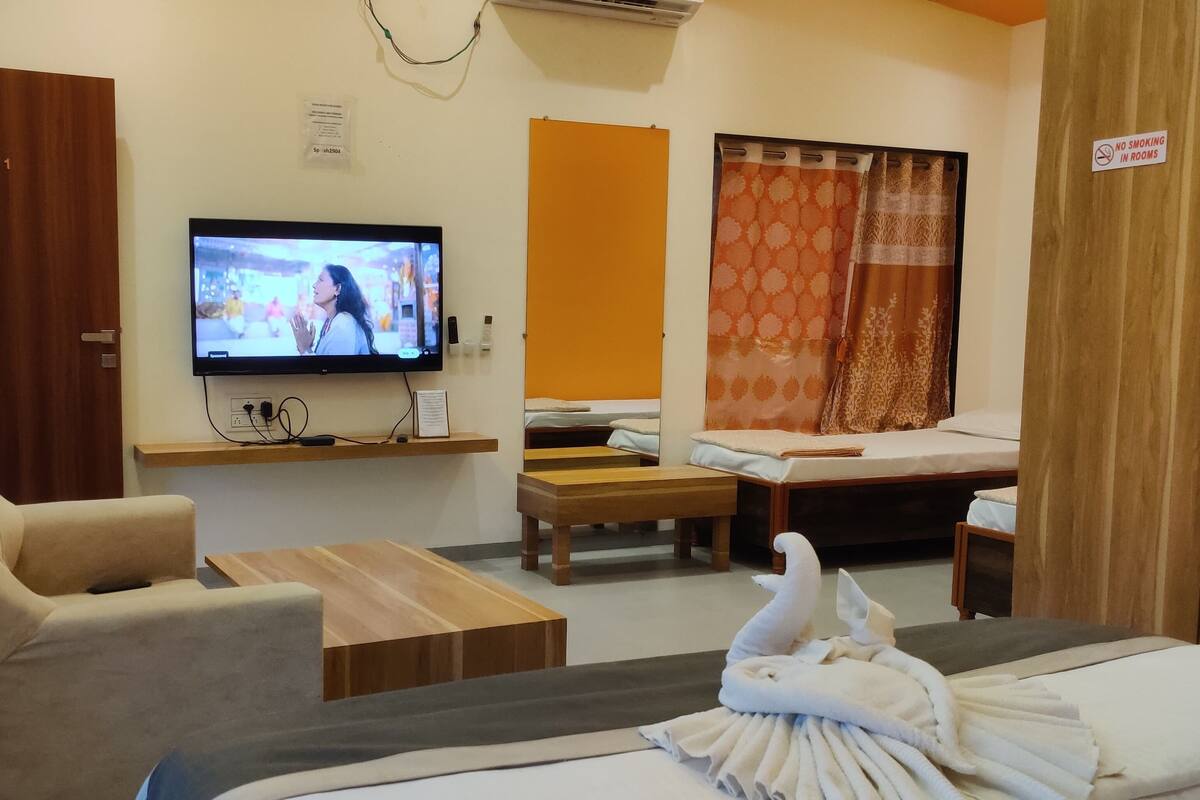 Quarto de hotel com televisão, sofá, mesa de madeira, cama e cortina de chuveiro.