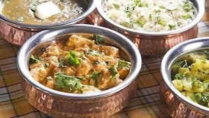 A variety of dishes served in traditional copper bowls, suggesting a cultural dining experience. - Supriti's Farmington Splash Resort (Karjat)