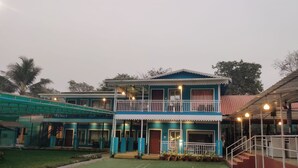 A two-story building with a balcony, a covered outdoor area, and a staircase leading to the upper floor. - Supriti's Farmington Splash Resort (Karjat)