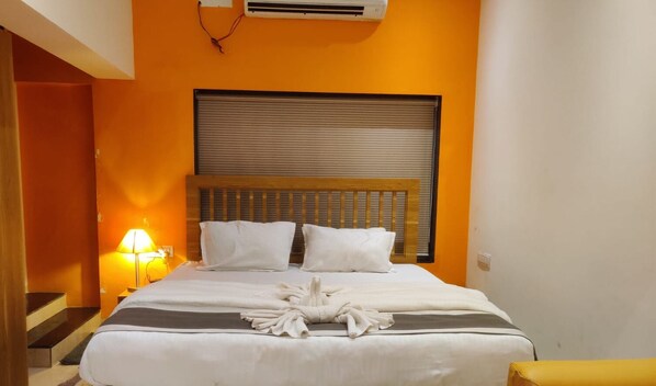 Ein Hotelzimmer mit Bett, Nachttisch mit Lampe und einer Klimaanlage an der Wand.