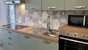 Una cocina moderna con gabinetes verdes, un lavamanos de acero inoxidable, un microondas y un horno.