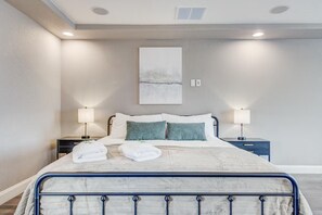 A neatly made bed with white linens and two green pillows, a bedside table with a lamp, and a wall-mounted artwork above the bed. - 5400sqft 6BR 5.5BA Theater, Office, Game Room // 10min to DIA & Downtown (Denver)