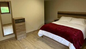 Un dormitori amb un llit, una petjaina i un mirall.